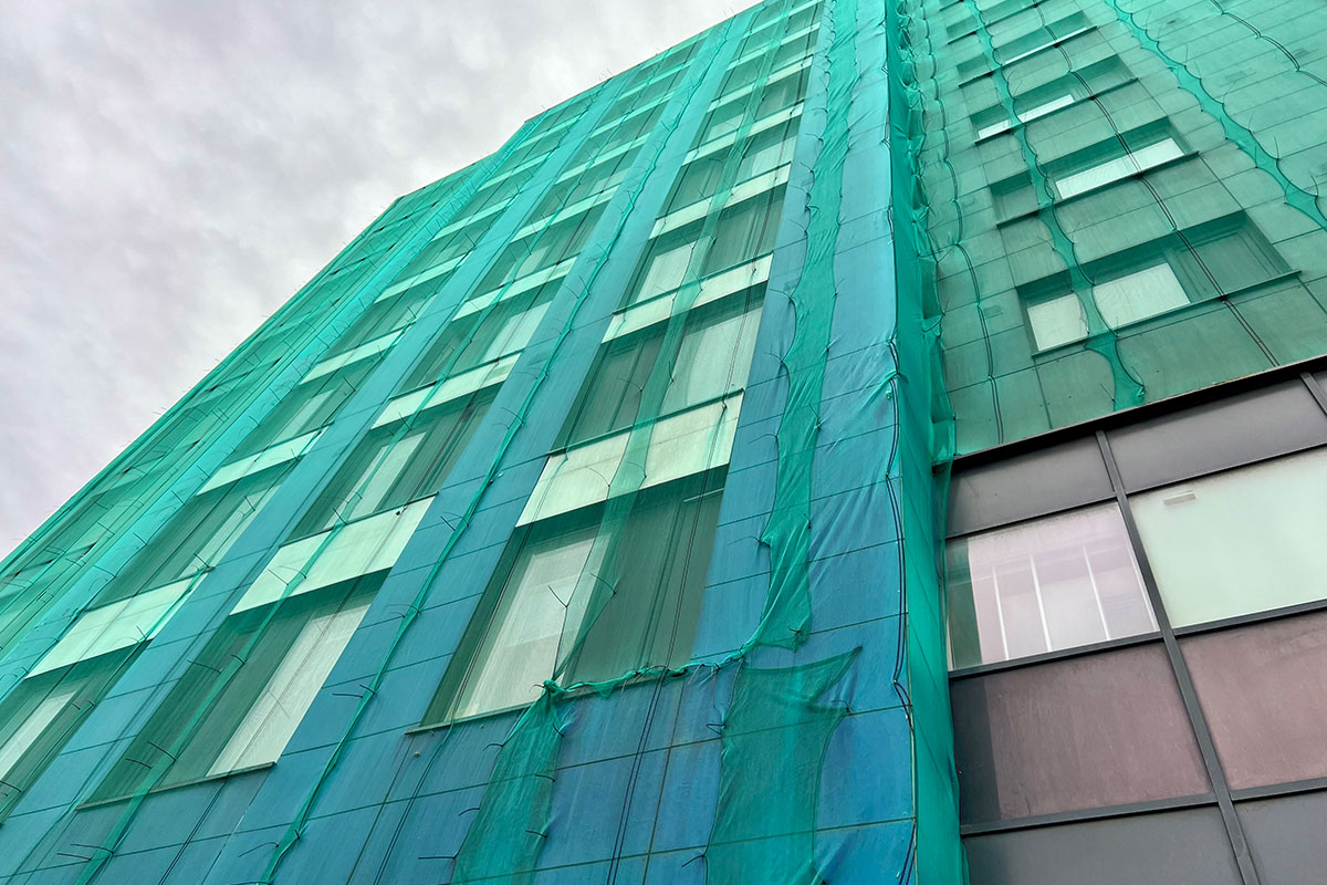 Tower block with green netting on the outside Tower block with green netting on the outside