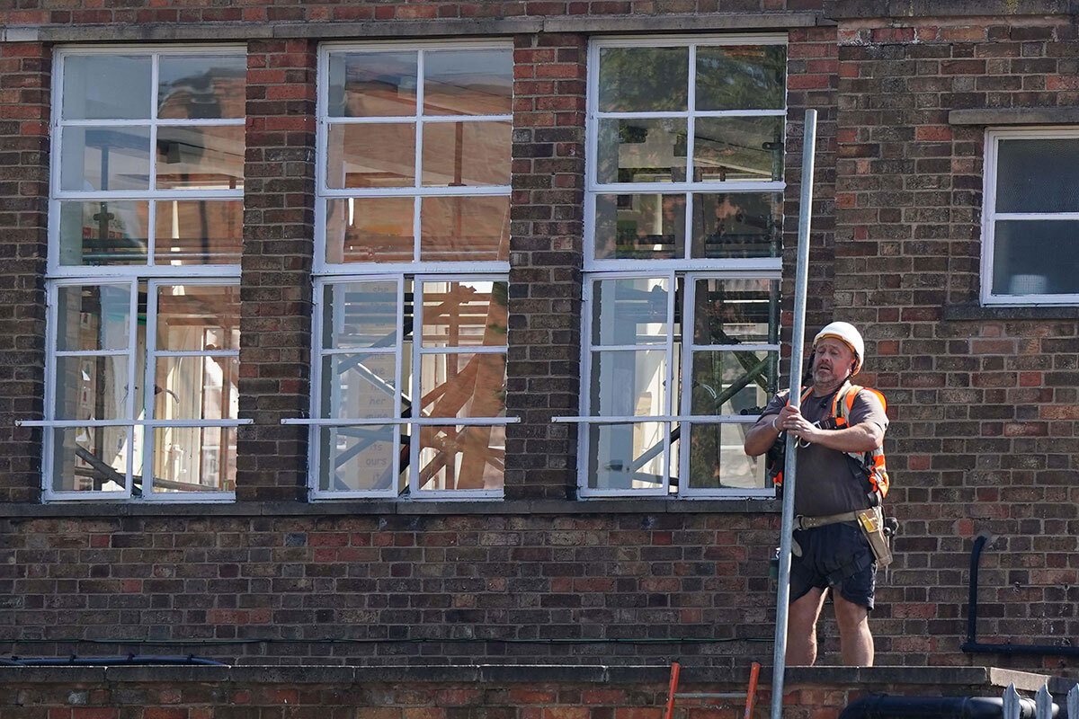 A construction worker holding a pole outside a school building