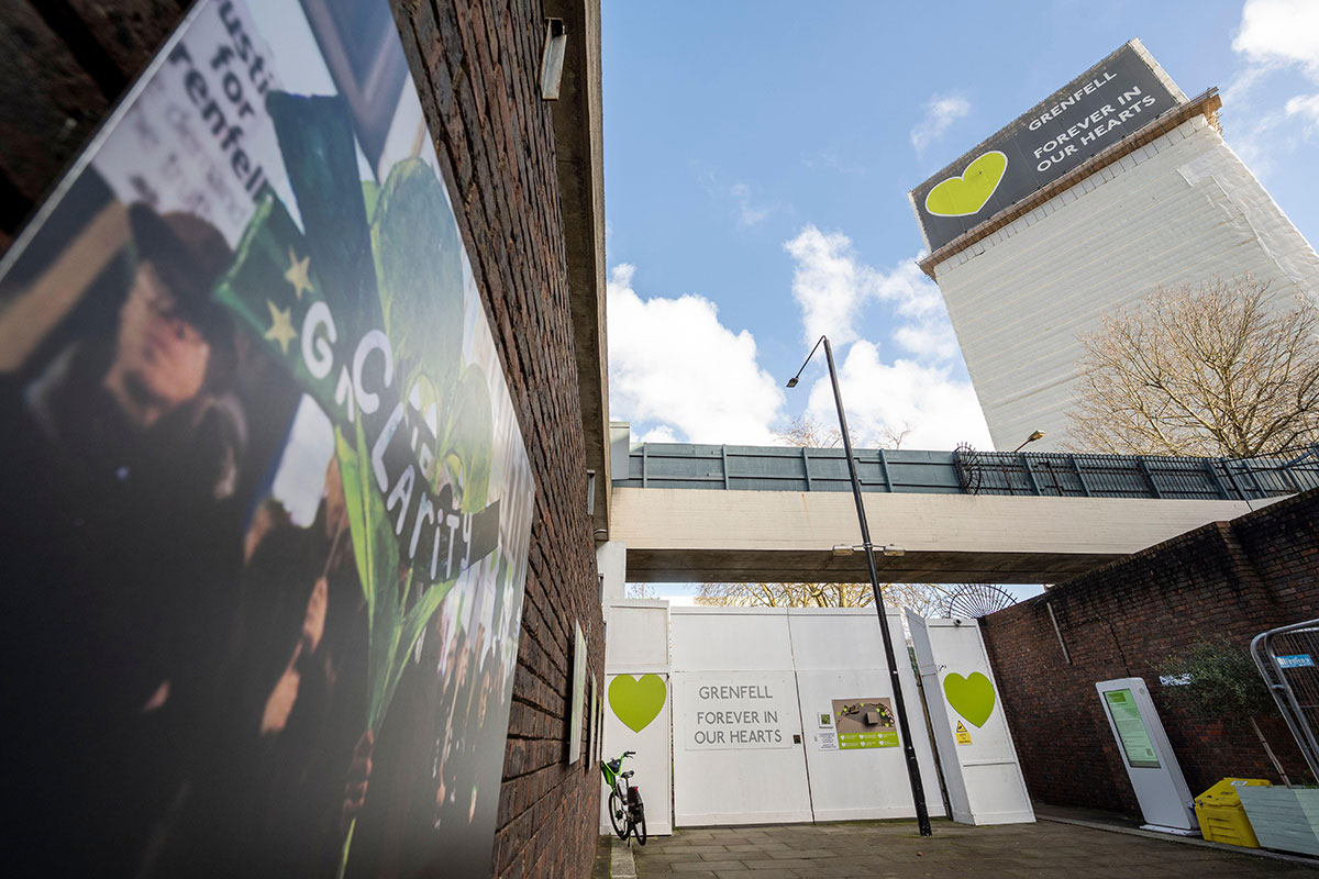 Grenfell Tower covered in scaffolding, with sign saying: Grenfell, forever in our hearts