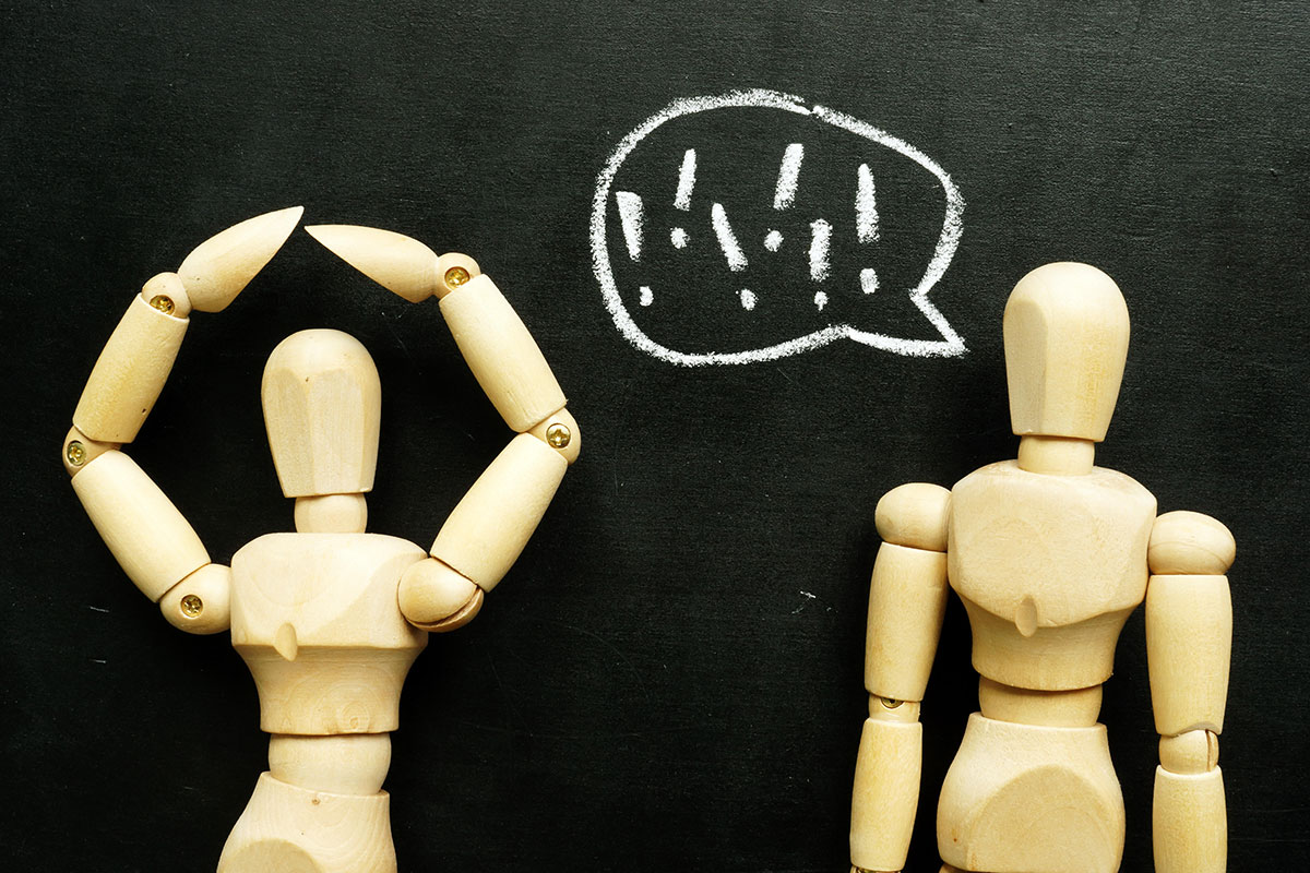 Two wooden figurines; one with a speech bubble