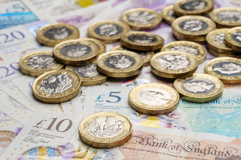 Pound coins on top of notes Pound coins on top of notes