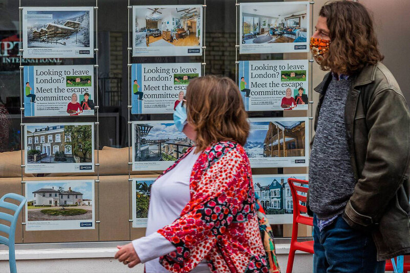 Two people wearing masks walk past an estate agent’s window during the Covid pandemic Two people wearing masks walk past an estate agent’s window during the Covid pandemic