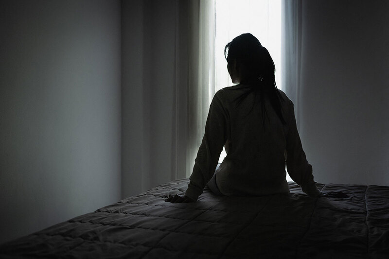 A woman sitting on a bed in silhouette