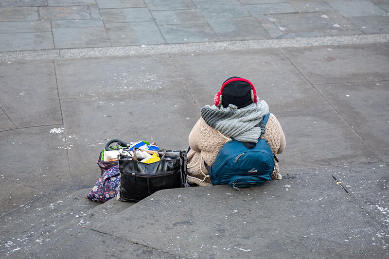 A woman sitting on steps with all her belongings