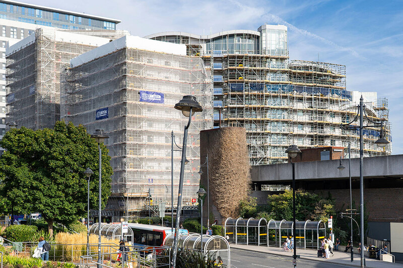 A building being remediated surrounded by covered scaffolding